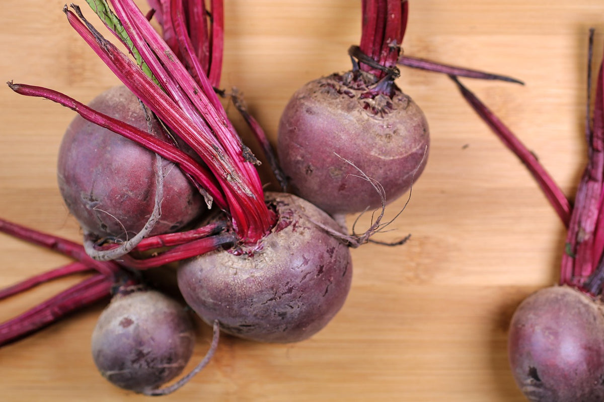 Beets with green tops on a wooden surface